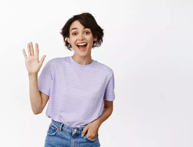 portrait-happy-brunette-girl-saying-hello-waving-you-laughing-seeing-friend-greeting-someone-standing-casual-clothes-against-white-background